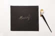 © Luca Di Lotti/Stocksy - the word 'Beauty' hand-written with silver ink, a tiny ink container and a nib mounted on a oblique holder are close to the paper.