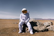 © Alexandr Ivanets/Stocksy - Person in space suit sitting on rock