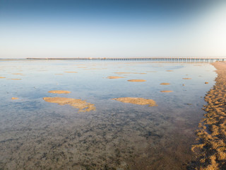 Wall Mural - Beautiful landscape of long pier and sandy beach in the ocean at sunset light