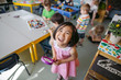 © Rob and Julia Campbell/Stocksy - Portrait of smiling girl holding magnifying glass in classroom
