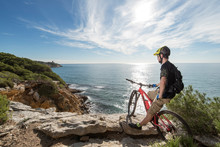 Cyclist Enjoying A Stop On A Cliff Above The Mediterranean Sea