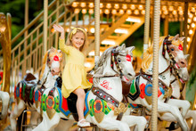 Adorable Little Girl Near The Carousel Outdoors In Paris, Baby Girl On The Carousel, Happy Healthy Baby Child Having Fun Outdoors On Sunny Day. Family Weekend Or Vacations