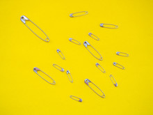 A Large Safety Pin Followed By Other Smaller Ones In Human Representation. Leadership Concept