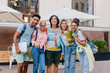 © Look! - Laughing asian boy in glasses and shorts embracing charming blonde girls in front of outdoor cafe. Joyful students came to open-air restaurant to celebrate end of exams