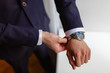 © korchemkin - Closeup designer watch on businessman hand, he looks on the time and hurrying. A man in an expensive suit straightens the cuffs of his shirt.