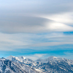 Square Striking mountain with rugged slopes under vast blue sky with clouds