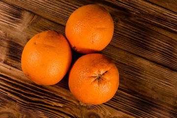 Three orange fruits on a wooden table. Top view