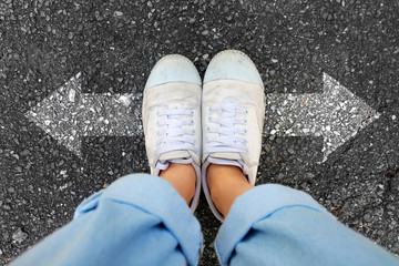 Selfie White Shoes. Woman Wear White Sneakers and Blue Jeans with Two Arrows Different Direction on Concrete Road Background Great for Any Use.