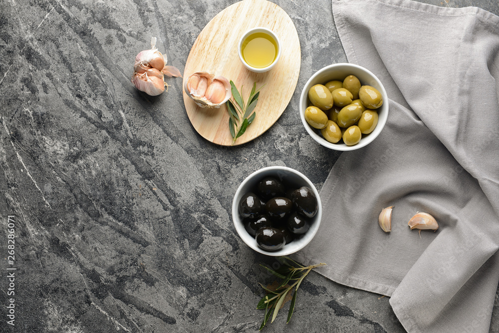 Tasty oil with olives and garlic on grey table