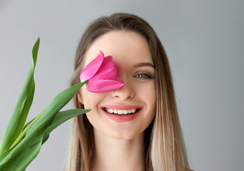 Poster - Young woman with beautiful tulip on light background