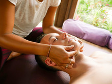Young Beautiful And Exotic Asian Thai Therapist Woman Giving Traditional Head And Facial Balinese Massage To Caucasian Man At Alternative Medicine Healing Spa