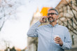 © cherryandbees - middle aged using cellphone and drinking coffee to go on street