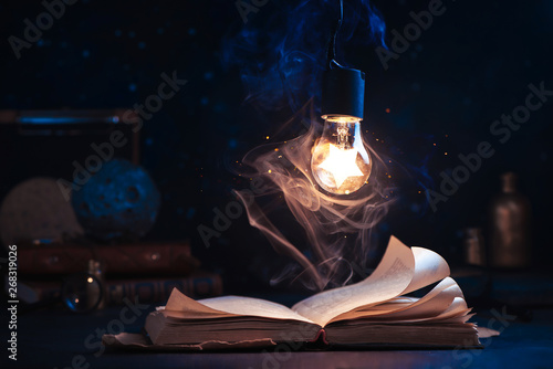 Fotomural An open book with lighting by a star inside a lightbulb
