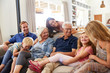 © Monkey Business - Multi-Generation Family Sitting On Sofa At Home Relaxing And Chatting