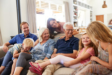 Multi-Generation Family Sitting On Sofa At Home Relaxing And Chatting