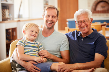 Wall Mural - Portrait Of Father With Adult Son And Teenage Grandson Relaxing On Sofa And Talking At Home