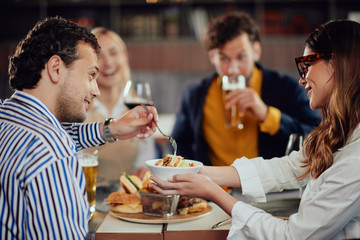 Poster - Multiethnic friends sitting at restaurant, drinking alcohol, chatting and having burgers for dinner.