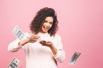 Cool rich girl! Money winner! Surprised beautiful african american woman in casual holding money in sunglasses isolated against pink background.