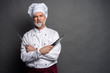 © opolja - Portrait of a mature chef cook holding knifes isolated on a black background.