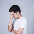 © narongchaihlaw - Portrait handsome young asian man wearing a white T-shirt stressed and anxiety isolated on grey background. Asian man people. business success concept.