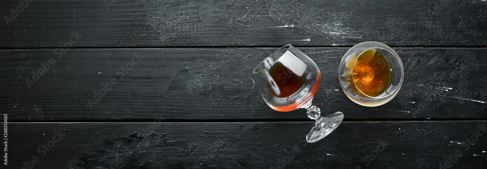 A glass of brandy on a black background. Top view. Free space for your text. - obrazy, fototapety, plakaty 