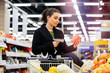 Woman holding bar code scanner and scanning products in store.