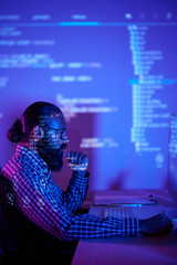 serious bearded programmer sitting at the table and looking at computer monitor in dark room, he dev