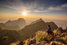 Man Sitting Back To Clear Sky Cloud Wait For Sunset At Top Of Wildlife Sanctuary Name Doi Luang Chiang Dao, Thailand With Shadow Of Mountain Layer And Sun Ray.