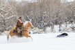 © Danita Delimont - Side view of cowboy riding horse during winter