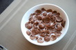 Breakfast Chocolate Cornflakes Cereal with milk in white bowl on the table
