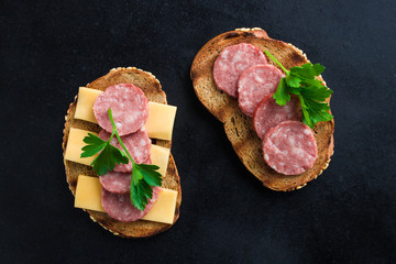 Wall Mural - open sandwiches  rye bread sliced salami cheese and parsley  black background