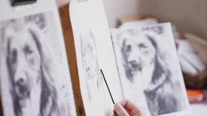 Wall Mural - Close Up Of Artist Sitting At Easel Drawing Picture Of Dog In Charcoal From Photograph