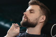 © ANR Production - Getting perfect shape. Close-up side view of young bearded man getting beard haircut by hairdresser or barber at barbershop