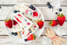 Healthy Strawberry Blueberry Yogurt Popsicles On A Plate, Top View Summer Table Scene Against A White Wood Background