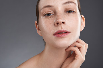attractive young woman with freckles touching her neck