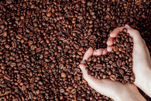 Coffee Beans In Man Palms In Form Of A Heart On Coffee Background
