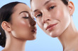 Close up portrait of attractive interracial women situating against blue background