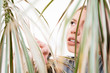 © Miljan Živković - Portrait of beautiful young woman with blonde hair trough the leaves of the plant in nature home in love