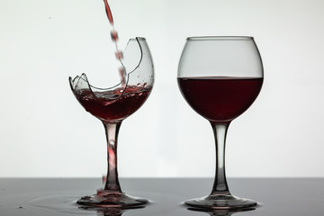 Wall Mural - Red wine pouring into broken wine glass on the wet surface. Rose wine pour