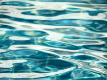 Abstract Water Ripples Background With Close Up Details Of Cool Blue Pools Of Water And White Patterns From Sunlight Reflections On The Water's Surface