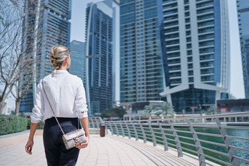 Wall Mural - Back view of young woman walking on city embankment.