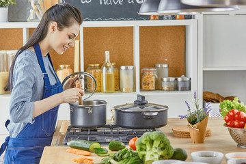 Wall Mural - Beautiful girl is tasting food and smiling while cooking in kit