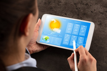 Wall Mural - business woman checking weekly weather forecast on tablet