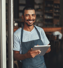 Wall Mural - A young african cafe entrepreneur holding digital tablet