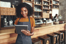 Successful small business owner using digital tablet in her cafe