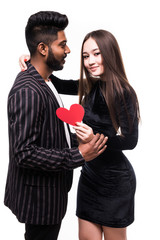 Two young smiling people in casual clothing hugging each other and holding heart isolated on white background