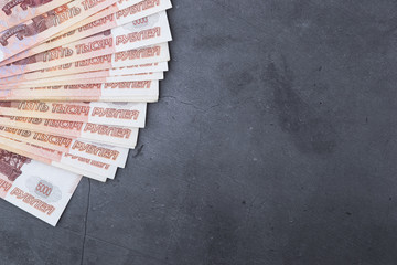 Big stack of Russian money banknotes of five thousand rubles lying fan on a grey cement background.