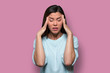Woman overwhelmed with stress and concern, confusion and doubt, hands to head, on pink background