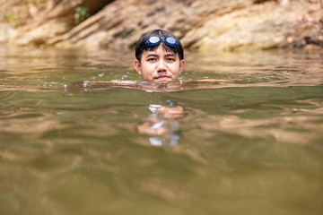 Asian man with goggles on head swimming in river, Handsome man enjoy swimming in water 