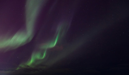 zigzag green flashes in sky above black horizon northern lights